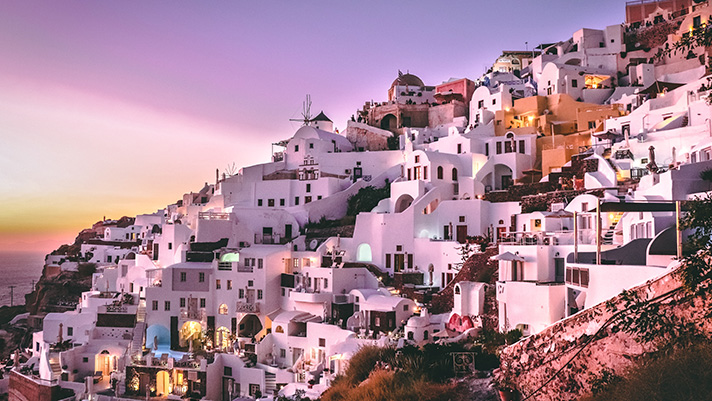 Discover the iconic white-washed buildings that cascade the hills of Santorini, Greece.